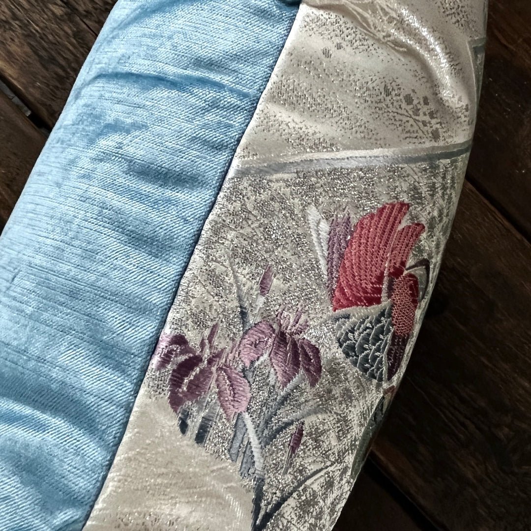 side view of cushion showing front ivory silk and blue velvet back